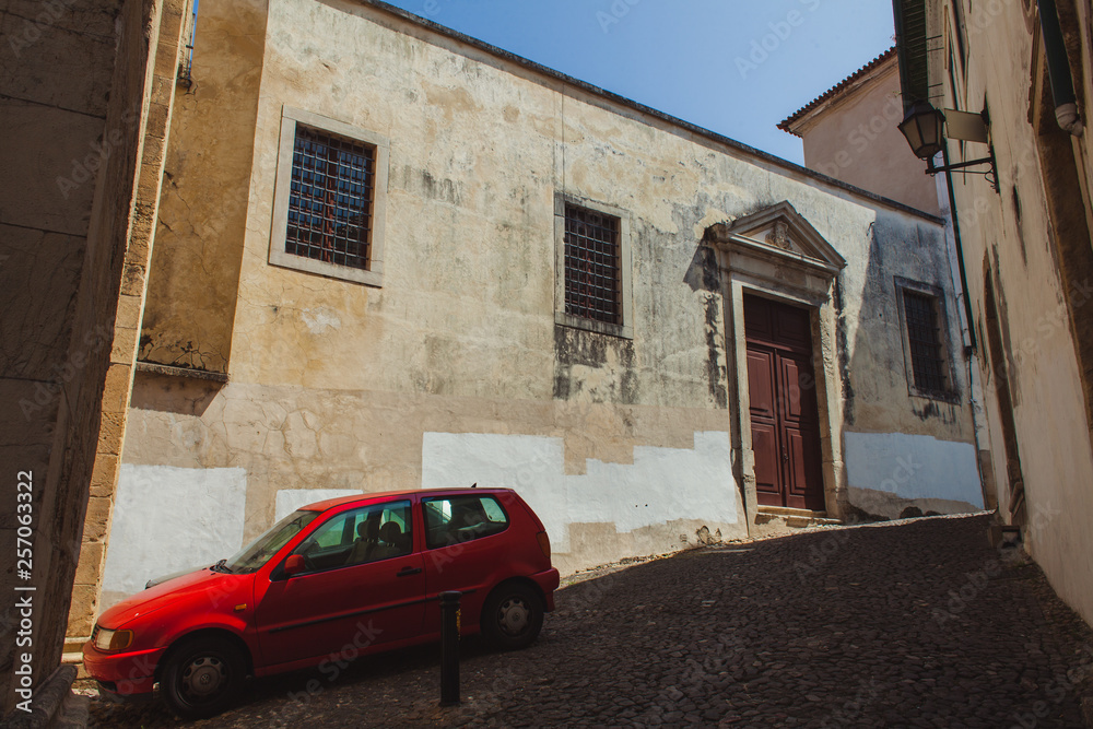 red car on a steep slope of a narrow street
