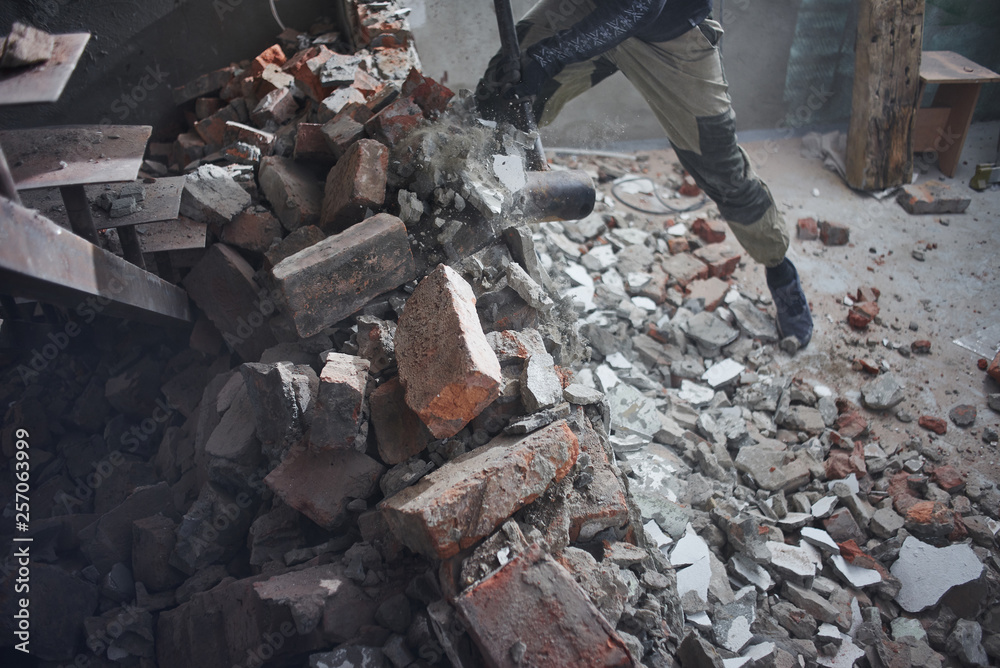 A man handyman breaks a brick wall with a hammer, builds and repairs his house A man handyman breaks a brick wall with a hammer, builds and repairs his house