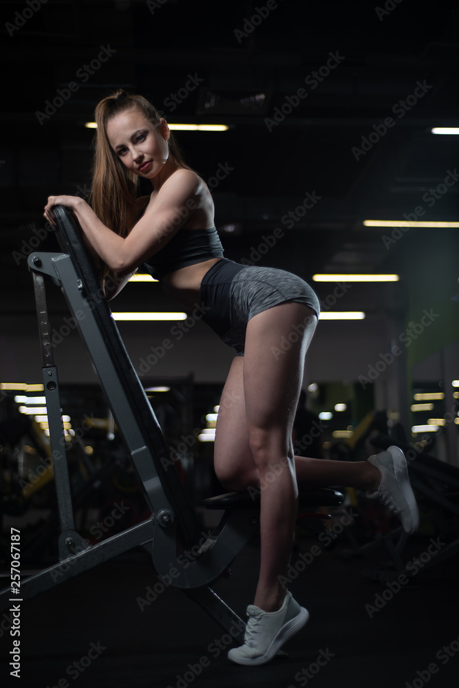 Fitness girl posing in the gym on the bench showing off her body