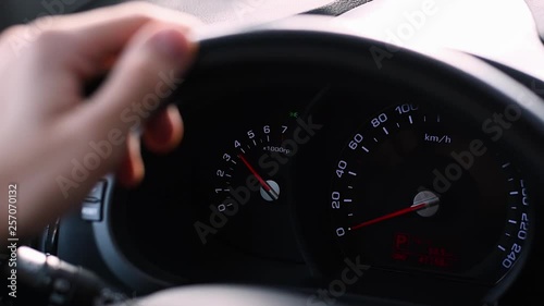 Young man standing on the parking, presses the accelerator pedal. The camera is aimed at the steering wheel with hand on it and on the cars dashboard. photo