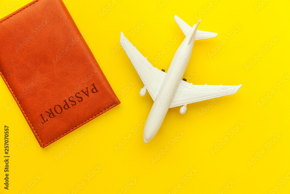 Travel by plane vacation summer weekend sea adventure trip journey ticket tour concept. Minimal simple flat lay with plane and passport on yellow trendy modern background. Tourist essentials
