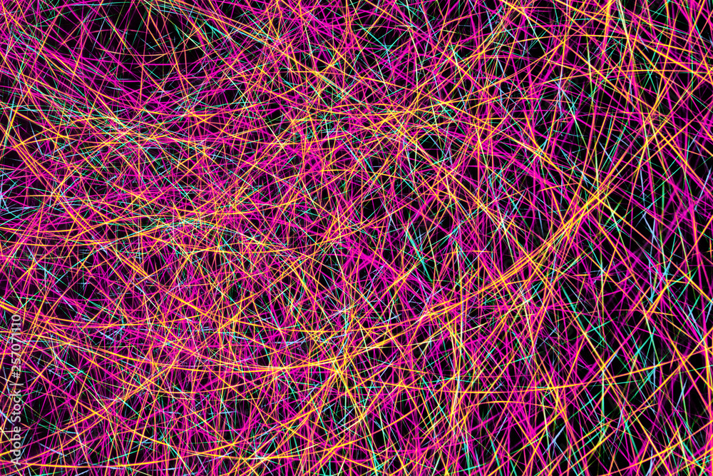 Colorful light painting abstract long exposure image with pink, blue, red and yellow lines on a black background