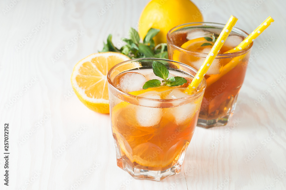 Fototapeta premium Refreshing citrus lemonade, summer drink. Ice tea with fresh lemon and mint on wooden background. Refreshment beverage concept.