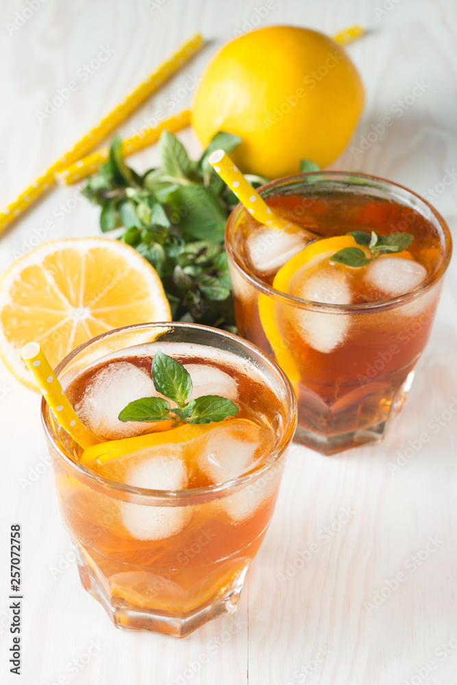 Fototapeta premium Refreshing citrus lemonade, summer drink. Ice tea with fresh lemon and mint on wooden background. Refreshment beverage concept.