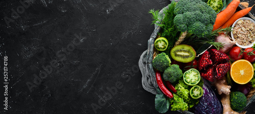 Fresh vegetables and fruits in a wooden box on a black background. Organic food. Top view. Free copy space.