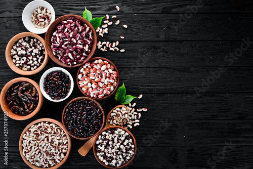 Colored raw beans. On a black wooden table. Top view. Free copy space.