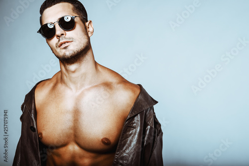 Fototapeta Portrait of handsome shirtless young man in glasses and leather coat