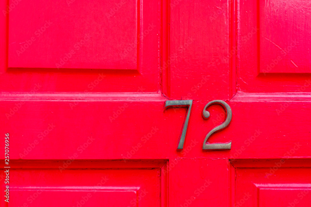 House number 72 with the seventy-two in bronze on a bright red door House number 72 with the seventy-two in bronze on a bright red door