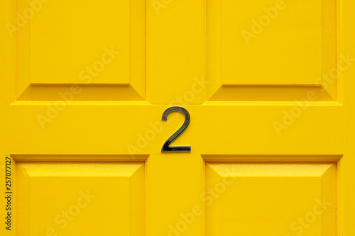 House number two with the 2 in the middle cross bar of a bright yellow painted house door photo