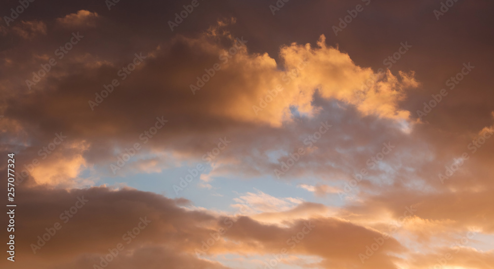 Dramatic clouds during the sunset. Through the dark clouds there is a blue sky visible_