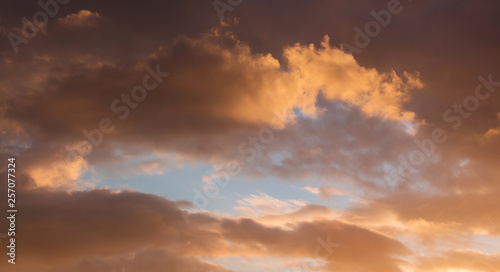 Dramatic clouds during the sunset. Through the dark clouds there is a blue sky visible_