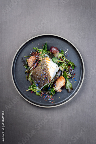 Fried Danish skrei cod fish filet with porcini mushroom and lettuce as closeup on a modern design plate photo