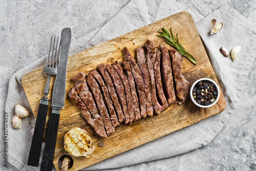 Flank steak on a wooden chopping Board. Gray background, top view, space for text