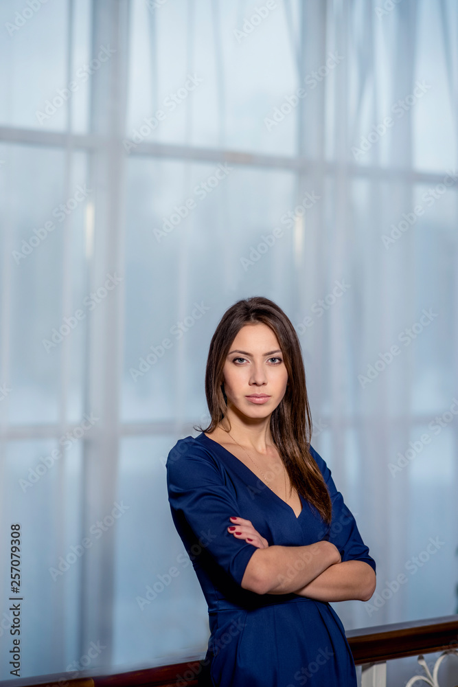 beautiful business woman with brunette hair in classic dark blue dress posing on light background in studio beautiful business woman with brunette hair in classic dark blue dress posing on light background in studio
