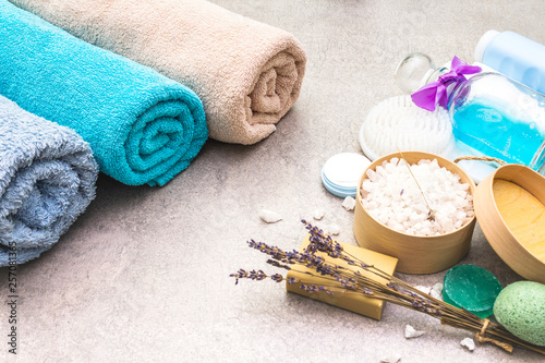 Spa concept set, natural ingredients. Bath towels, sea salt with lavender, natural olive soap, shower gel, cream and brush. On a stone background