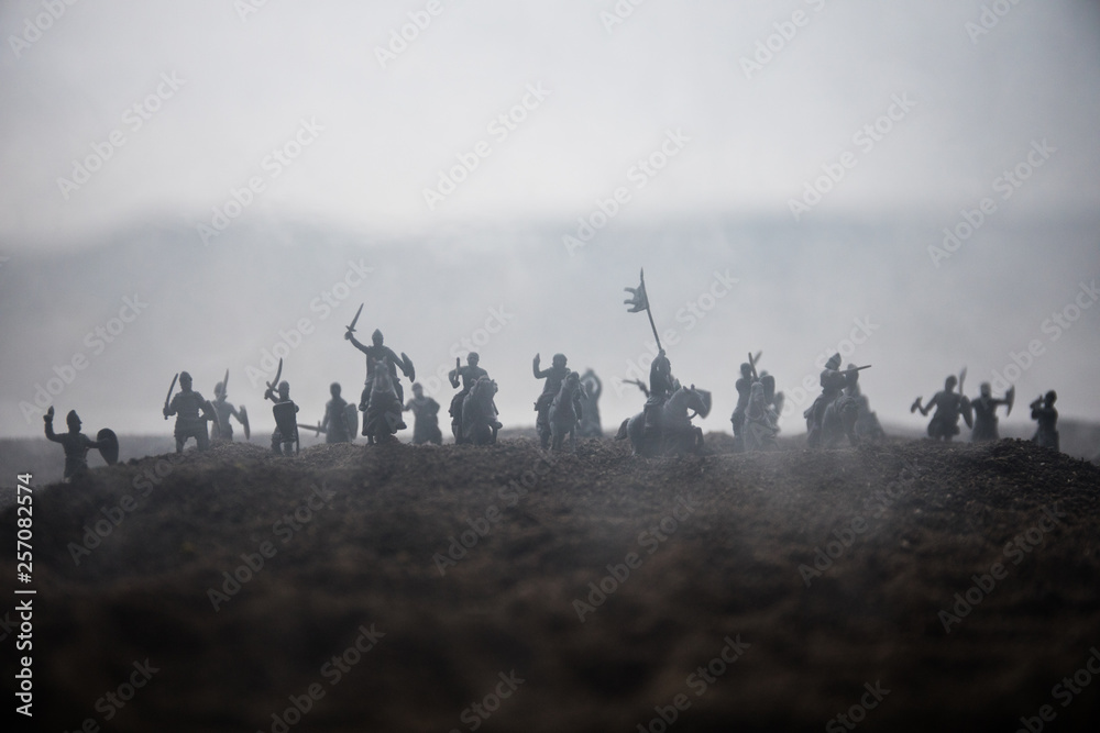 Fototapeta premium Medieval battle scene with cavalry and infantry. Silhouettes of figures as separate objects, fight between warriors on sunset foggy background.
