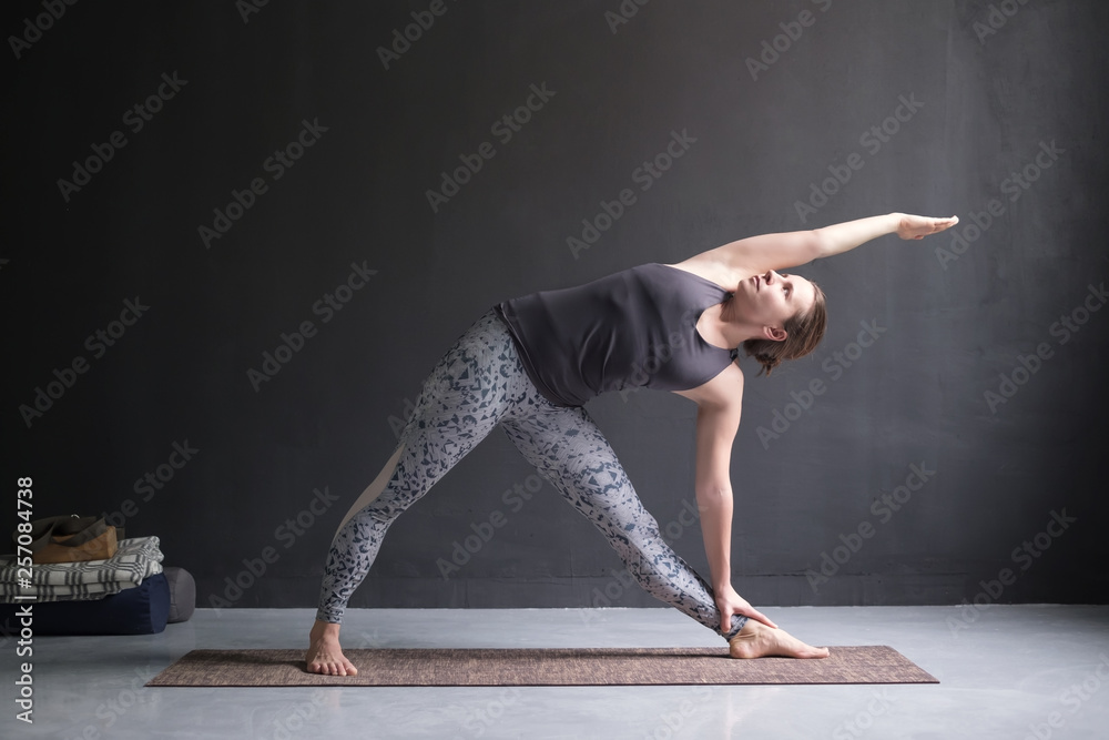 woman practicing yoga, doing Utthita Trikonasana pose