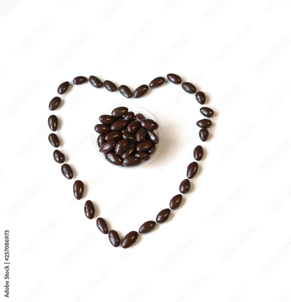 Nuts arranged in heart shape on background. Food image close up candy, chocolate milk, extra dark almond nuts. Love Texture on white grey table top view Nuts arranged in heart shape on background. Food image close up candy, chocolate milk, extra dark almond nuts. Love Texture on white grey table top view