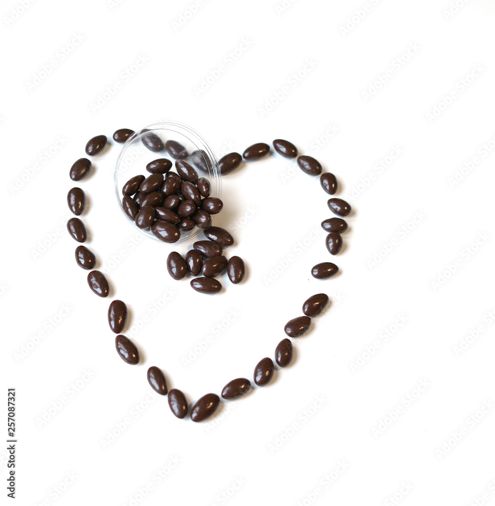 Nuts arranged in heart shape on background. Food image close up candy, chocolate milk, extra dark almond nuts. Love Texture on white grey table top view Nuts arranged in heart shape on background. Food image close up candy, chocolate milk, extra dark almond nuts. Love Texture on white grey table top view