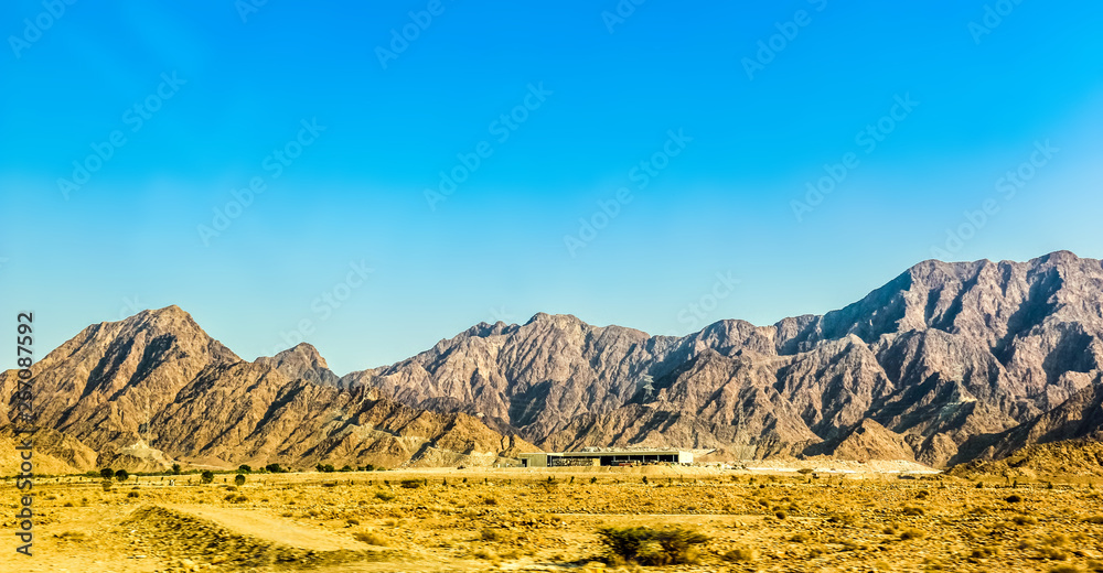 Geological landscape of Jabal Jais characterised by dry and rocky mountains, Road between mud mountains in Ras Al Khaimah, United Arab Emirates