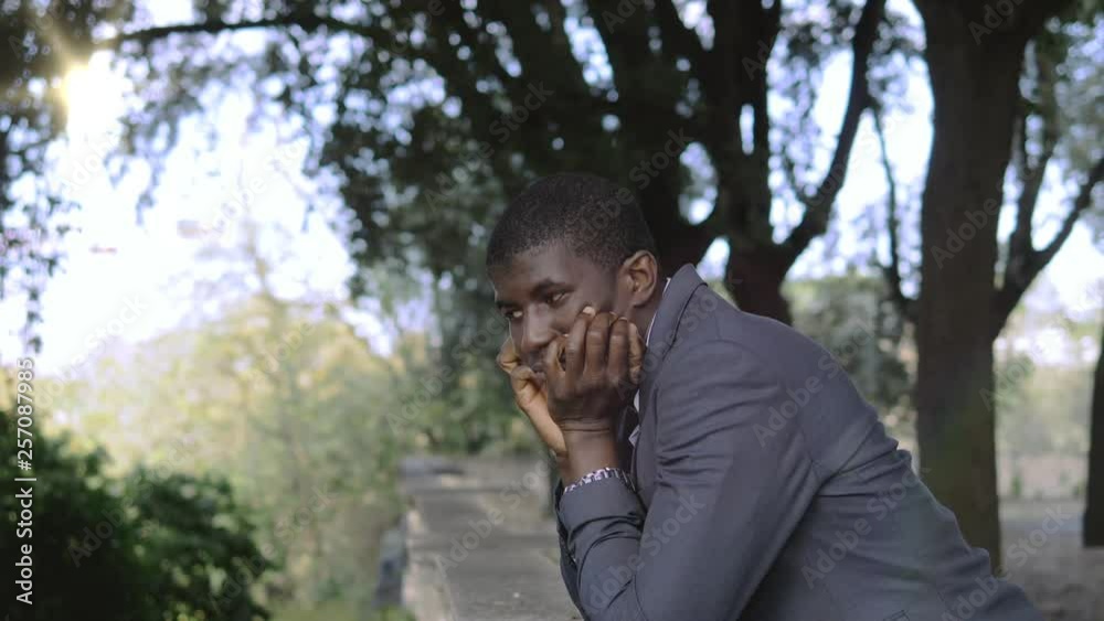 Thoughtful sad lonely black african business man in the park.Worries,thoughts Thoughtful sad lonely black african business man in the park.Worries,thoughts