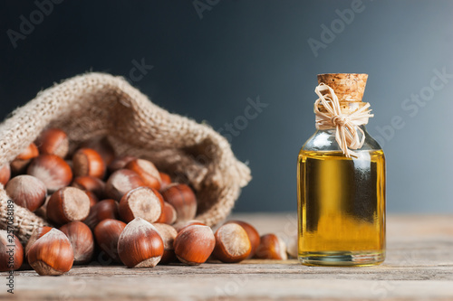 Hazelnuts, filbert in burlap sack and hazelnut oil in glass of bottle on wooden backdrop. heap or stack of hazelnuts. Hazelnut background, healty food photo