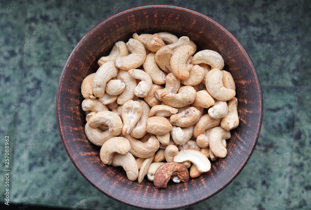 Healthy food for background image close up cashew nuts. Nuts texture on white grey table top view on the cup plate Healthy food for background image close up cashew nuts. Nuts texture on white grey table top view on the cup plate