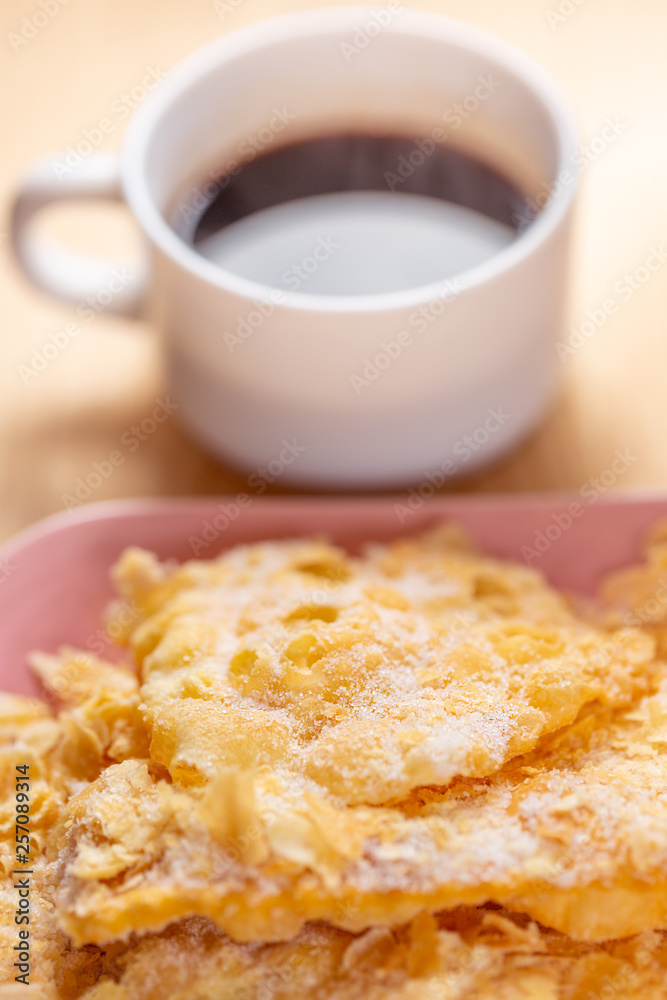 Food and dessert. Crackled crispy cookies with sugar on a plate and a cup of coffee on a wooden table. Blurry background and soft focus. Close-up. Food and dessert. Crackled crispy cookies with sugar on a plate and a cup of coffee on a wooden table. Blurry background and soft focus. Close-up.