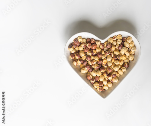 Nuts arranged in heart  on background. Healthy Food image close up hazelnuts. Love Texture on white grey table top view