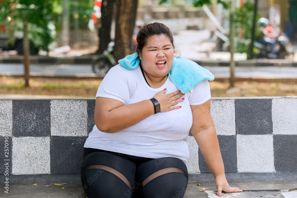 Overweight woman having heart attack at park foto de Stock Adobe Stock(02)