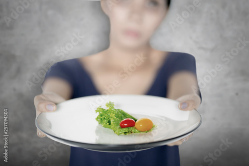 Young woman showing small portion salad