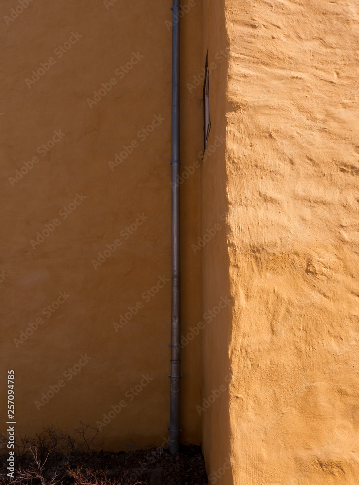 Eine Hauswand mit Lehm verputzt und gelb angestrichen. Eine Hauswand mit Lehm verputzt und gelb angestrichen.