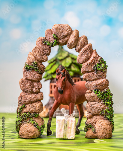 Gift horse under an arch in front of a mythical forest house. photo