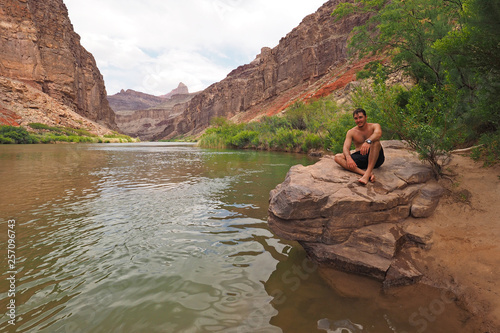 Young man resting by the Colorado River just above Hance Rapids during a multi-day hike in Grand Canyon National Park, Arizona.