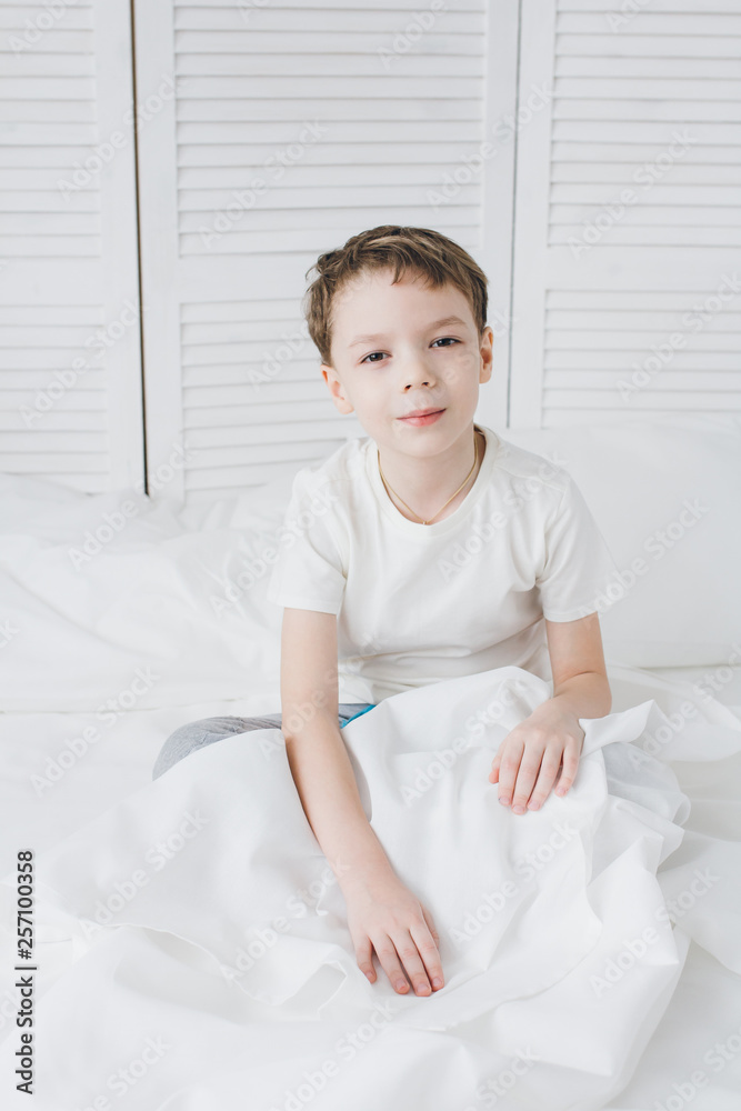 Fototapeta premium Cute boy woke up in the morning and sleepy sitting in bed