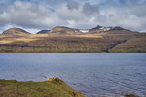 Landscape Picture of mountains without trees on island Vidoy from Bordoy in Faroe islands close to waterfall Fossa. Pasture or grazing land with primitive breed of faroese sheep taken in windy spring 