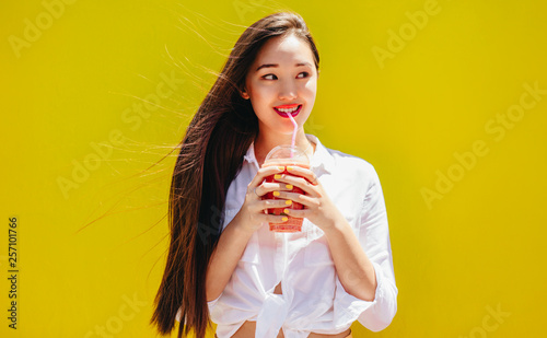 Portrait of smiling woman enjoying a glass of juice