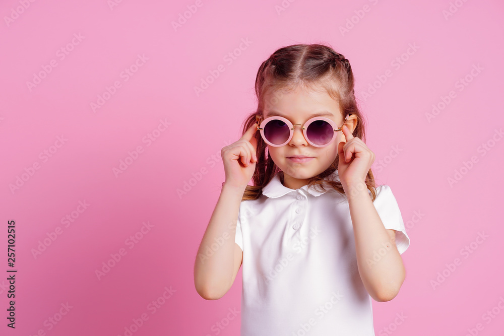 Portrait of beautiful smiling cute model in trendy round sunglasses. Casual 7 y.o. girl posing isolated on pink background. Portrait of beautiful smiling cute model in trendy round sunglasses. Casual 7 y.o. girl posing isolated on pink background.