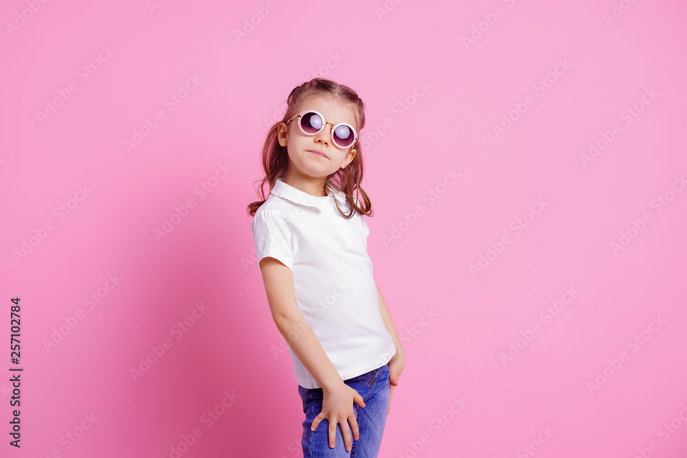 Portrait of beautiful smiling cute model in trendy round sunglasses. Casual 7 y.o. girl posing isolated on pink background. Portrait of beautiful smiling cute model in trendy round sunglasses. Casual 7 y.o. girl posing isolated on pink background.