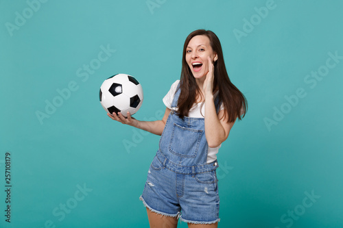 Funny young woman football fan cheer up support favorite team with soccer ball speaking with hand gesture isolated on blue turquoise background in studio. People emotions sport family leisure concept. © ViDi Studio