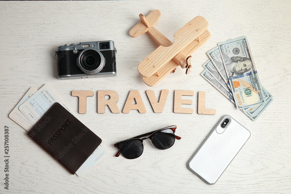 Flat lay composition with word TRAVEL, camera and passport on wooden background. Tourist agency Flat lay composition with word TRAVEL, camera and passport on wooden background. Tourist agency