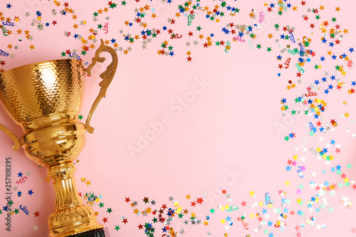 Trophy and frame of confetti on color background, top view with space for text. Victory concept photo