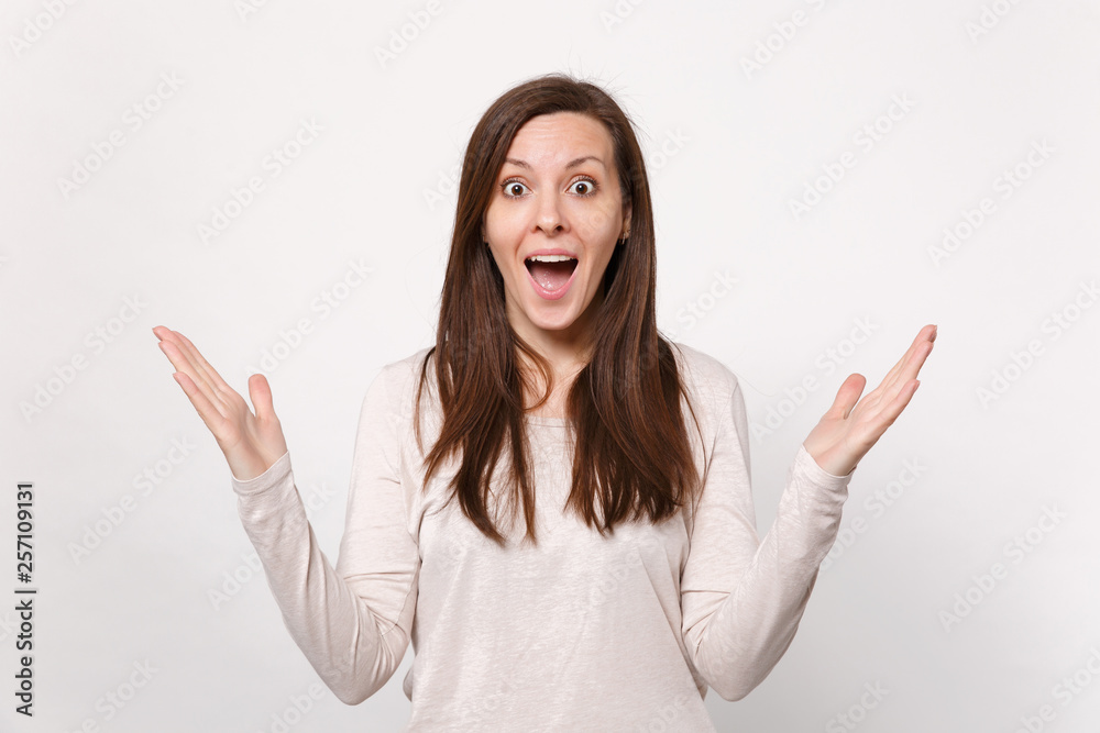 Portrait of surprised young woman in light clothes keeping mouth wide open, spreading hands isolated on white wall background in studio. People sincere emotions, lifestyle concept. Mock up copy space. Portrait of surprised young woman in light clothes keeping mouth wide open, spreading hands isolated on white wall background in studio. People sincere emotions, lifestyle concept. Mock up copy space.