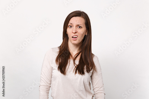 Portrait of puzzled concerned dissatisfied young woman in light clothes looking camera isolated on white wall background in studio. People sincere emotions lifestyle concept. Mock up copy space.