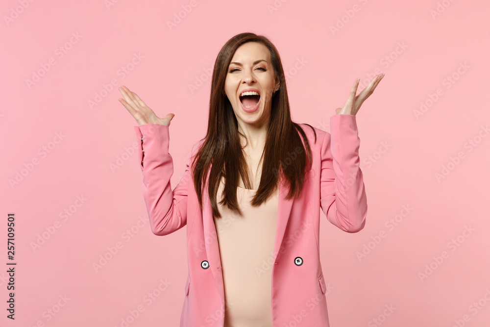 Portrait of cheerful happy screaming young woman wearing jacket, spreading hands isolated on pastel pink wall background in studio. People sincere emotions, lifestyle concept. Mock up copy space.