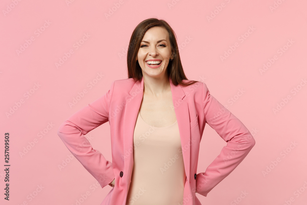 Portrait of smiling beautiful young woman in jacket standing with arms akimbo on waist isolated on pastel pink wall background in studio. People sincere emotions lifestyle concept. Mock up copy space. Portrait of smiling beautiful young woman in jacket standing with arms akimbo on waist isolated on pastel pink wall background in studio. People sincere emotions lifestyle concept. Mock up copy space.