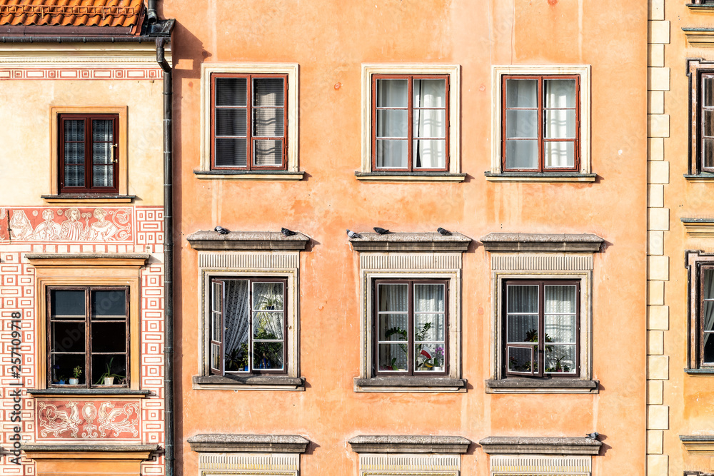 Fototapeta premium Warsaw, Poland old town market square with closeup of historic street town architecture windows pattern of red orange yellow light color