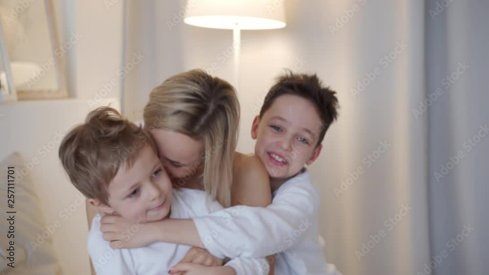 Happy family - mother with two sons hugging in bed Happy family - mother with two sons hugging in bed
