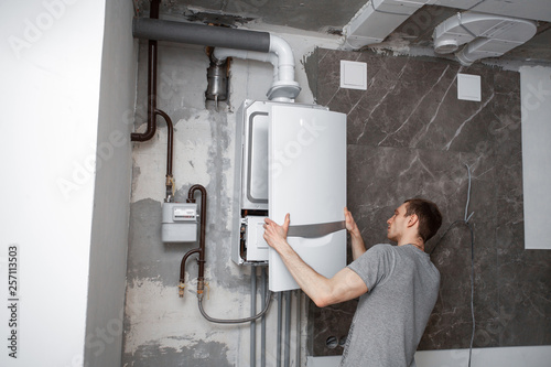 Installation and setting the new gas boiler for hot water and heating. Technician servicing the house heating system. photo