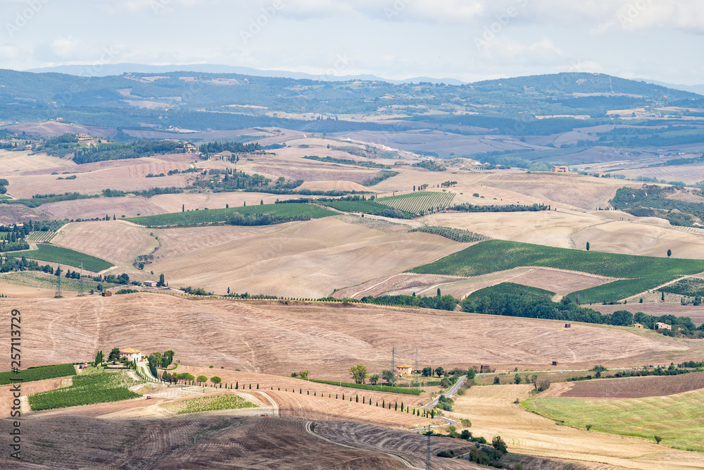 Val D'Orcia countryside high angle view in Tuscany, Italy with rolling plowed brown hills and villas with farm landscape picturesque meadow fields